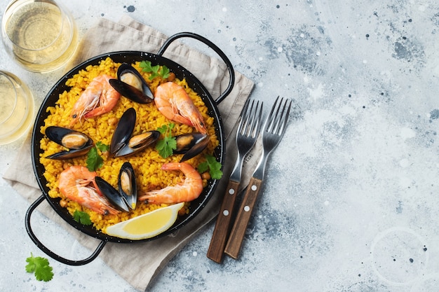 Traditionelle spanische Paella mit Meeresfrüchten in Pfanne mit Kichererbsen, Garnelen, Muscheln, Tintenfisch. Ansicht von oben.
