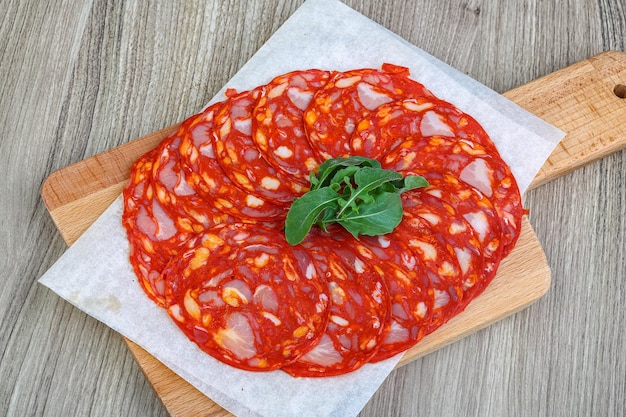 Traditionelle spanische Salami-Chorizo-Wurst auf dem Holzhintergrund mit Rucola-Blättern