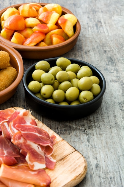 Traditionelle spanische Tapas. Kroketten, Oliven, Omelett, Schinken und Patatas Bravas auf Holztisch