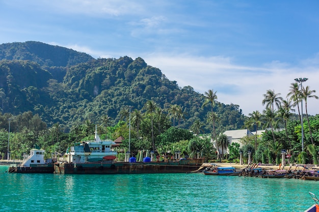 Traditionelle thailändische Fischerboote mit bunten Bändern umwickelt, vor dem Hintergrund einer tropischen Insel,