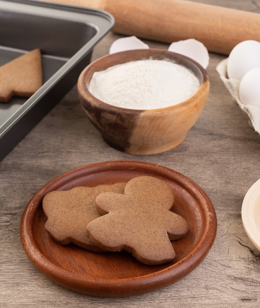 Traditionelle Weihnachtslebkuchenplätzchen über einem Holztisch mit Zutaten.