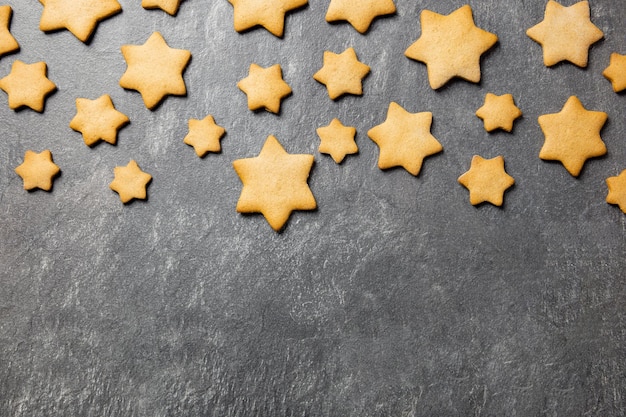 Traditionelle Weihnachtsplätzchen mit Lebkuchensternen auf dunklem Steinhintergrund Draufsicht Kopierbereich