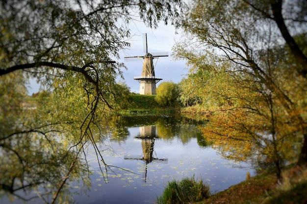 Foto traditionelle windmühle reflektiert auf dem see gegen das meer