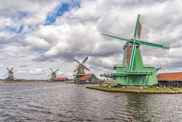 Traditionelle Windmühlen am Fluss gegen bewölkten Himmel in Zaanse Schans