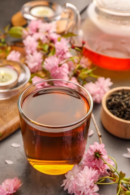 Traditionelle Zeremonie Tasse gebrühten Tee, Teekanne und Sakura-Blumen auf grauem Tisch in Nahaufnahme