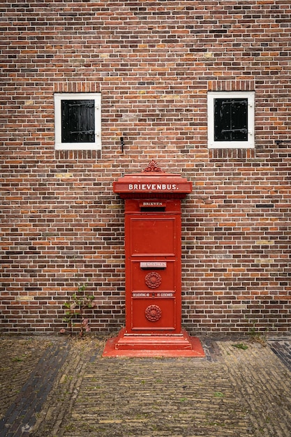 Traditioneller alter holländischer roter Briefkasten, der in einer Cotswold-Steinmauer montiert ist