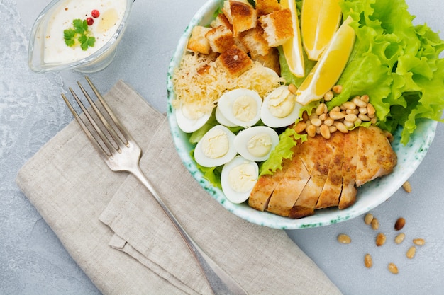 Traditioneller Caesar-Salat mit Wachteleiern und Pinienkernen in einer leichten Keramikschale Auf einer grauen Stein- oder Betonoberfläche