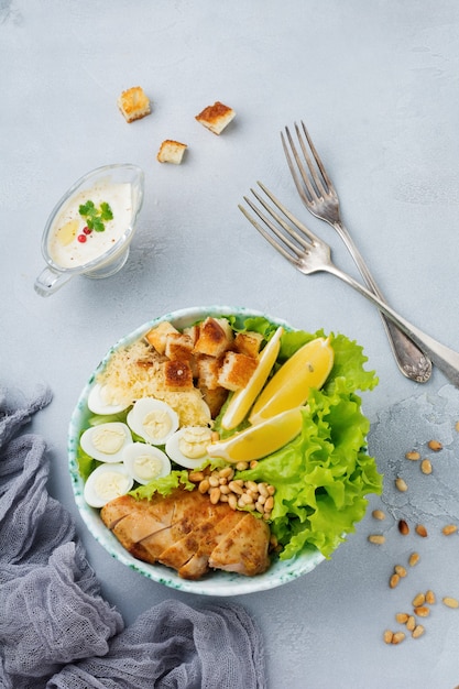 Traditioneller Caesar-Salat mit Wachteleiern und Pinienkernen in einer leichten Keramikschale Auf einer grauen Stein- oder Betonoberfläche