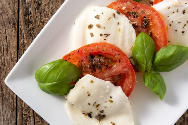 Traditioneller Caprese-Salat mit Tomaten und Mozzarella auf rustikalem Holztisch