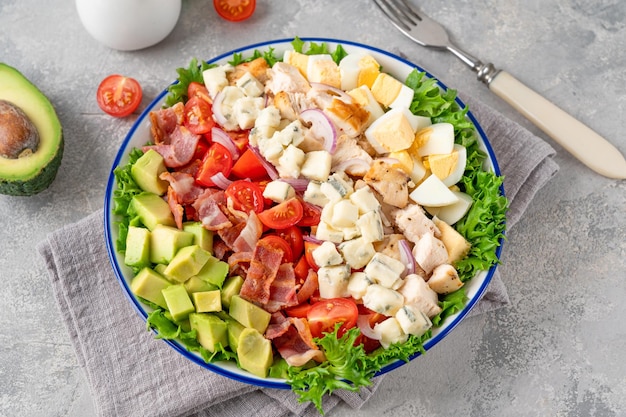 Traditioneller Cobb-Salat mit gebratenem Hähnchen, Avocado, frischen Tomaten, Eiern, Speck und Käse auf einem Teller