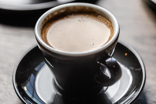 Traditioneller Espresso-Kaffee in einer schwarzen Tasse auf einem Tisch in einem Café