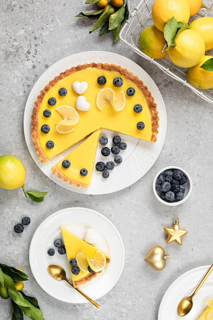 Traditioneller französischer Zitronenkuchen mit Blaubeeren auf einem weißen Steingrund Vertikal