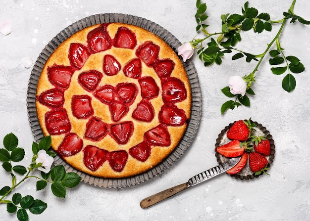 Traditioneller frisch gebackener Erdbeerquarkkuchen mit verziert mit Blumen auf grauem Hintergrund