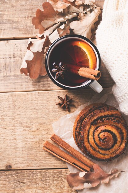 Traditioneller Glühwein im Becher mit Gebäck und Gewürzen auf Holz