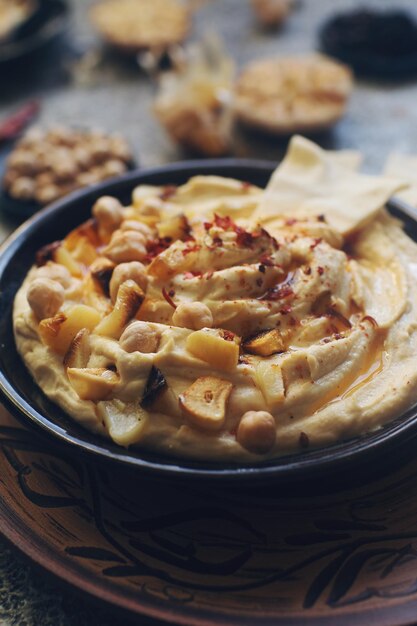 Traditioneller hausgemachter Hummus aus dem Nahen Osten, dekoriert mit Kichererbsen und Knoblauch