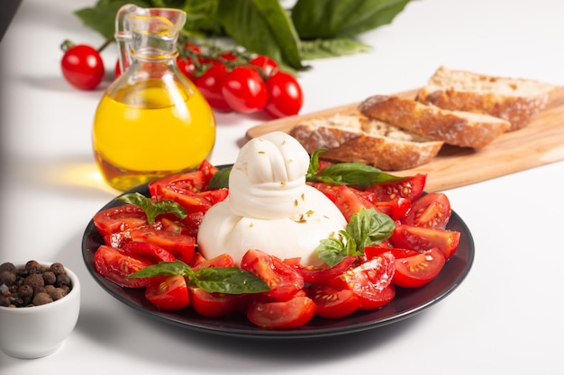 Traditioneller italienischer Burrata-Käse mit Salat aus köstlichen Kirschtomaten, Basilikumblättern und Olivenöl