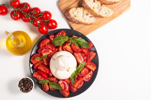 Traditioneller italienischer Burrata-Käse mit Salat aus köstlichen Kirschtomaten, Basilikumblättern und Olivenöl