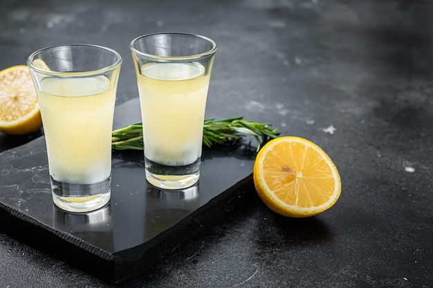 Traditioneller italienischer Zitronenalkohol Likör Limoncello mit Zitrone und Rosmarin Schwarzer Hintergrund Draufsicht Kopierbereich