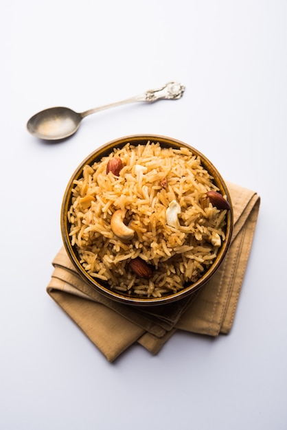 Foto traditioneller jaggery-reis oder gur wale chawal in hindi, serviert in einer schüssel mit löffel. selektiver fokus