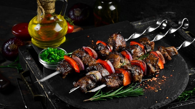 Traditioneller kebab saftige schweinefleischspieße mit gemüse auf einer schwarzen steinplatte barbecue draufsicht freier platz für text