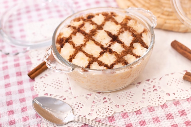 Traditioneller portugiesischer süßer Reis-Dessert auf einem Tisch mit Zimtstangen.