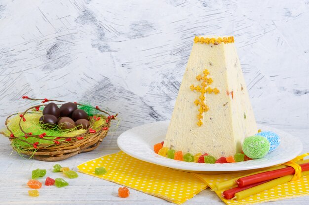 Traditioneller Quark-Osterkuchen mit kandierten Früchten und Schokoladeneiern auf dem Feiertagslichthintergrund.