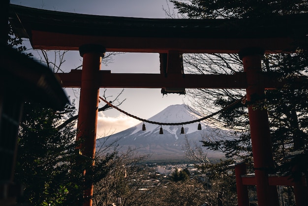 Traditioneller roter Torii und Fuji-Berg mit Schneedecke bei Sonnenuntergang, schöner Wahrzeichen-Reiseort. Japanische Landschaft der Winterjahreszeiten mit einem Tori-Tor