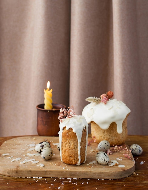 traditioneller russischer Osterkuchen mit Zuckerguss und Wachteleiern und einer brennenden Kerze auf einem Holzständer