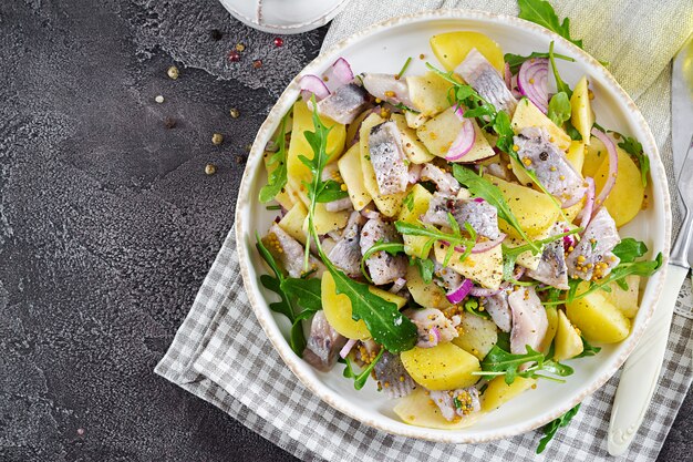 Foto traditioneller salat aus gesalzenem heringsfilet, frischen äpfeln, roten zwiebeln und kartoffeln. koscheres essen. skandinavische küche. draufsicht. flach liegen