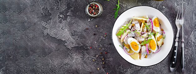 Traditioneller Salat aus gesalzenem Heringsfilet, frischen Äpfeln, roten Zwiebeln und Eiern.