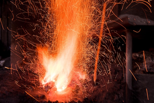 Traditioneller Schmiedeofen mit brennendem Feuer Brennendes Feuer im Ofen in Schmiede, Werkstatt. Schmiedeausrüstungskonzept