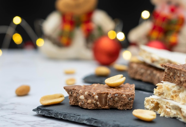 Traditioneller spanischer süßer Turron auf einem Tisch mit Lichtern und Weihnachtsdekorationen