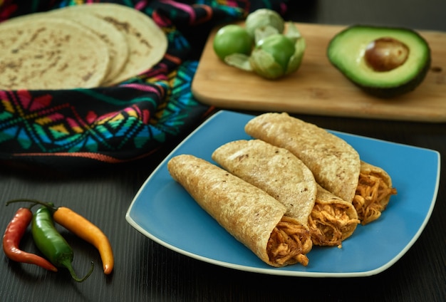 Traditioneller Teller mit goldenen Tacos des mexikanischen Essens mit Hühnchen