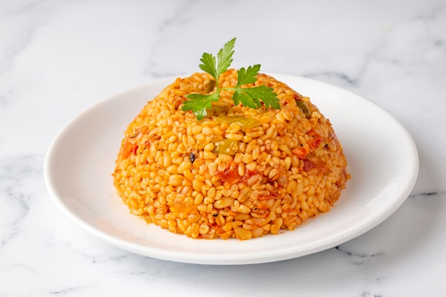 Traditioneller türkischer Bulgur-Pilaw mit Tomatensoße im Teller (türkischer Name; meyhane pilavi)