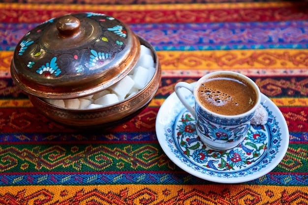 Traditioneller türkischer Kaffee in einer keramischen Kaffeetasse auf traditioneller Textur und Muster der Tischdecke