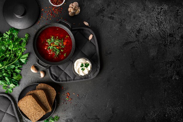 Traditioneller ukrainischer russischer Borschtsch auf dunklem Hintergrund. Borschtsch mit Sauerrahm. Rote-Bete-Borschtsch mit Petersilie. Foto in hoher Qualität