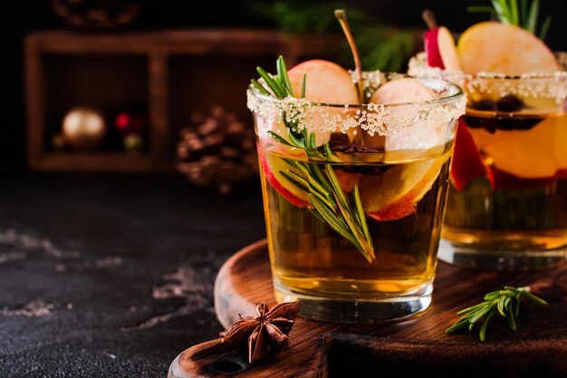 Traditioneller Weihnachtsapfelpunsch mit Zimt, Anis und Rosmarinzweigen auf dunklem Tischtisch