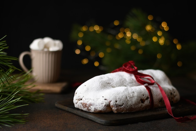 Traditioneller Weihnachtsstollen verziertes Feiertagsseil auf einem festlich gedeckten Tisch mit Girlandenkaffeetasse