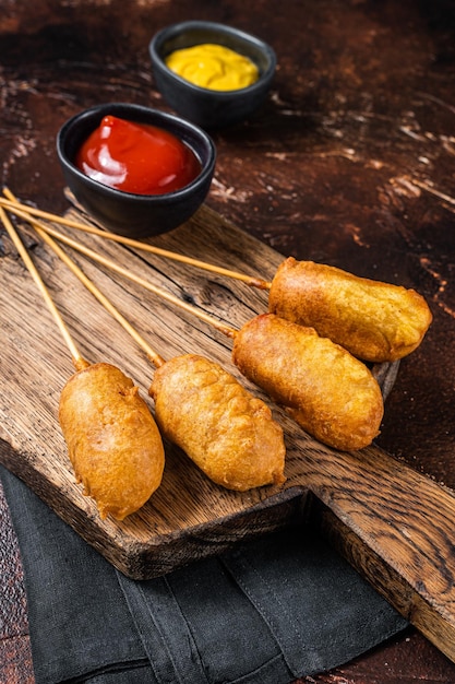 Traditionelles amerikanisches Straßen-Junk-Food Frittierte Maishunde mit Senf und Ketchup Dunkler Hintergrund Ansicht von oben