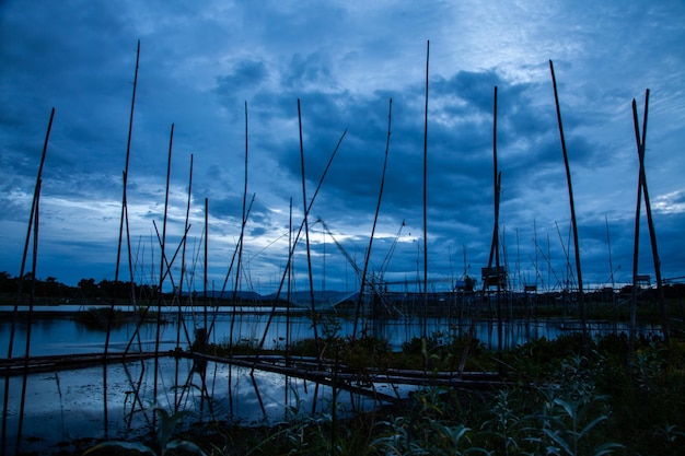 Traditionelles Angelwerkzeug oder Bambusfischfalle auf Sonnenuntergangslicht-Landschaftssilhouette