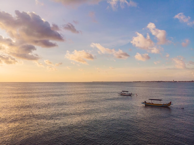 Traditionelles balinesisches Boot Jukung am Strand von Jimbaran bei Sonnenuntergang in Bali, Indonesien. Foto von der Drohne