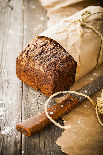 Traditionelles Brot mit Samen, die in Papier auf altem Holztisch eingewickelt werden