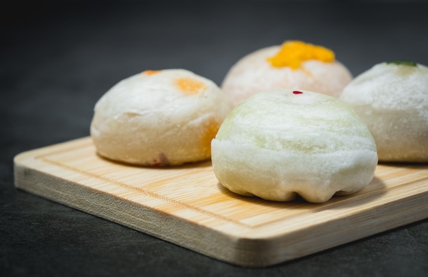 Traditionelles chinesisches Gebäck auf Holzplatte vor dunklem Hintergrund für Lebensmittel- und Bäckereikonzept