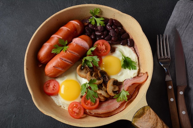 Traditionelles englisches Frühstück mit Speck, Spiegeleiern, Würstchen, gebackenen Bohnen, Pilzen