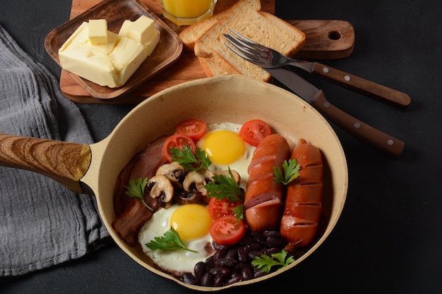 Traditionelles englisches Frühstück mit Speck, Spiegeleiern, Würstchen, gebackenen Bohnen, Pilzen