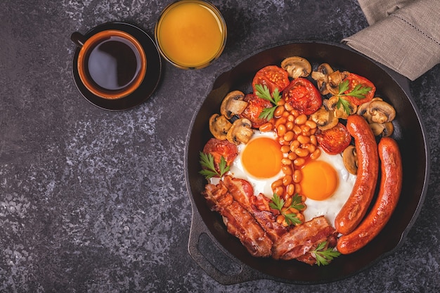 Traditionelles englisches Frühstück mit Spiegeleiern, Würstchen, Bohnen, Pilzen, gegrillten Tomaten und Speck