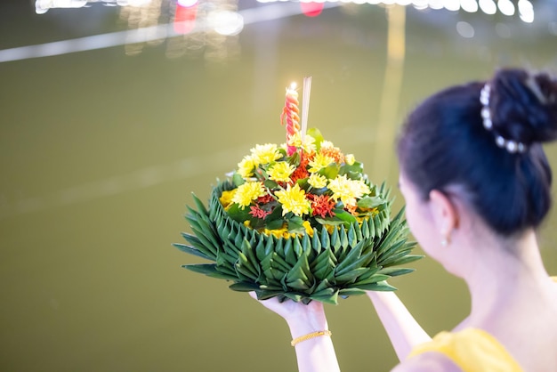 Traditionelles Fest von Loy Krathong Eine schöne Thailänderin hält in einer Vollmondnacht bei Loy Krathong-Feierlichkeiten in Thailand eine Krathong-Zierform aus Bananenblättern