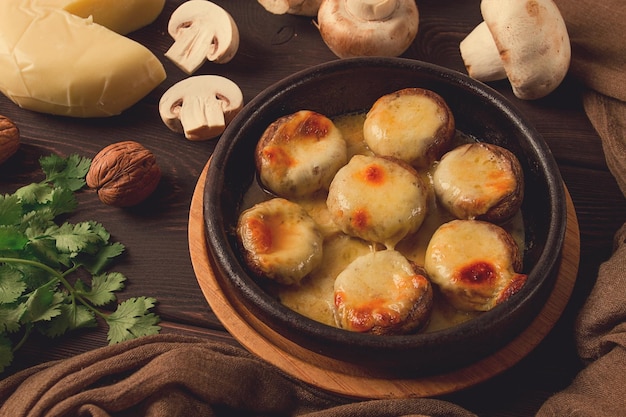 Traditionelles georgisches Gericht, Vorspeise, gefüllte Pilze Sulguni-Käse, gebacken in einer Ketzi-Tonpfanne auf einem Holztisch, Nahaufnahme, keine Menschen