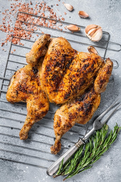 Traditionelles Grillhähnchen mit Spatchcocked auf dem Grill. Grauer Hintergrund. Ansicht von oben.