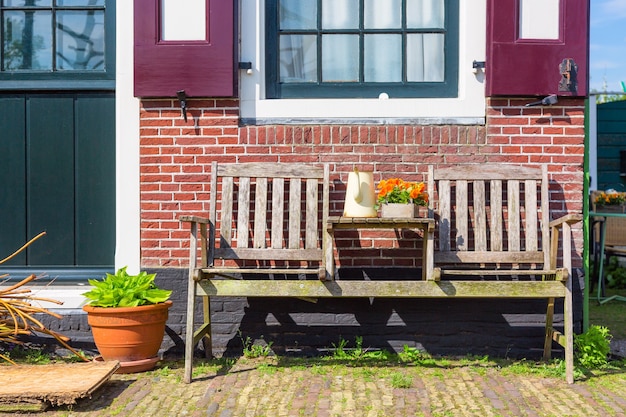 Traditionelles holländisches Haus mit Holzbank und Blumen im Dorf Zaanse Schans, Niederlande. Berühmter Tourismusort.